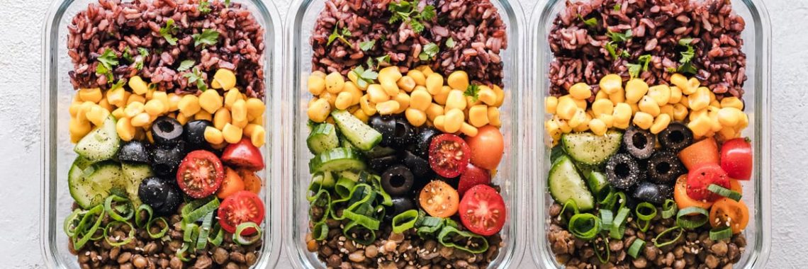 Colorful healthy meal prep with corn, olives, tomatoes, and lentils in glass containers. Perfect for mindful eating.